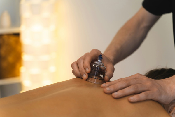 massage therapit applying cupping device to shoulders